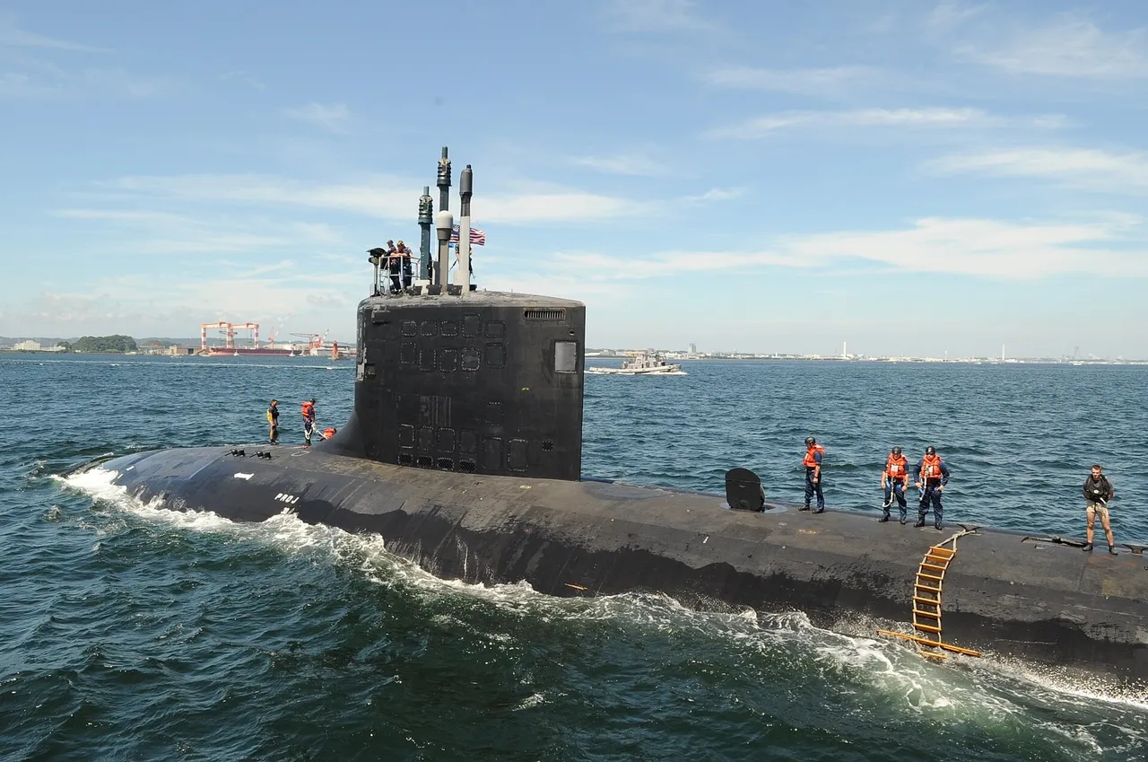 A black Virginia-class submarine on the surface with crew in orange life vests on deck and an American flag on the sail