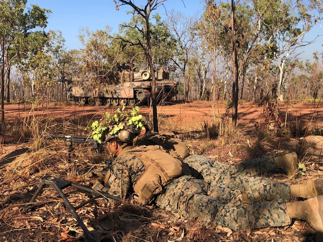 US Marines on foot beside an Australian Army M1A1 Abrams tank at the Mount Bundey training range.