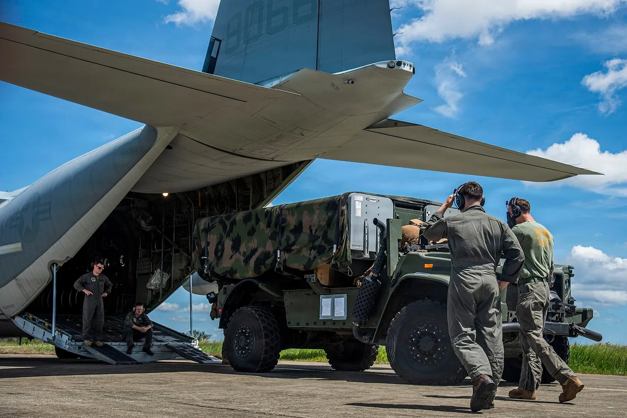 US Marines unloading a missile launcher vehicle from the rear ramp of a KC-130J transport aircraft on an island airstrip