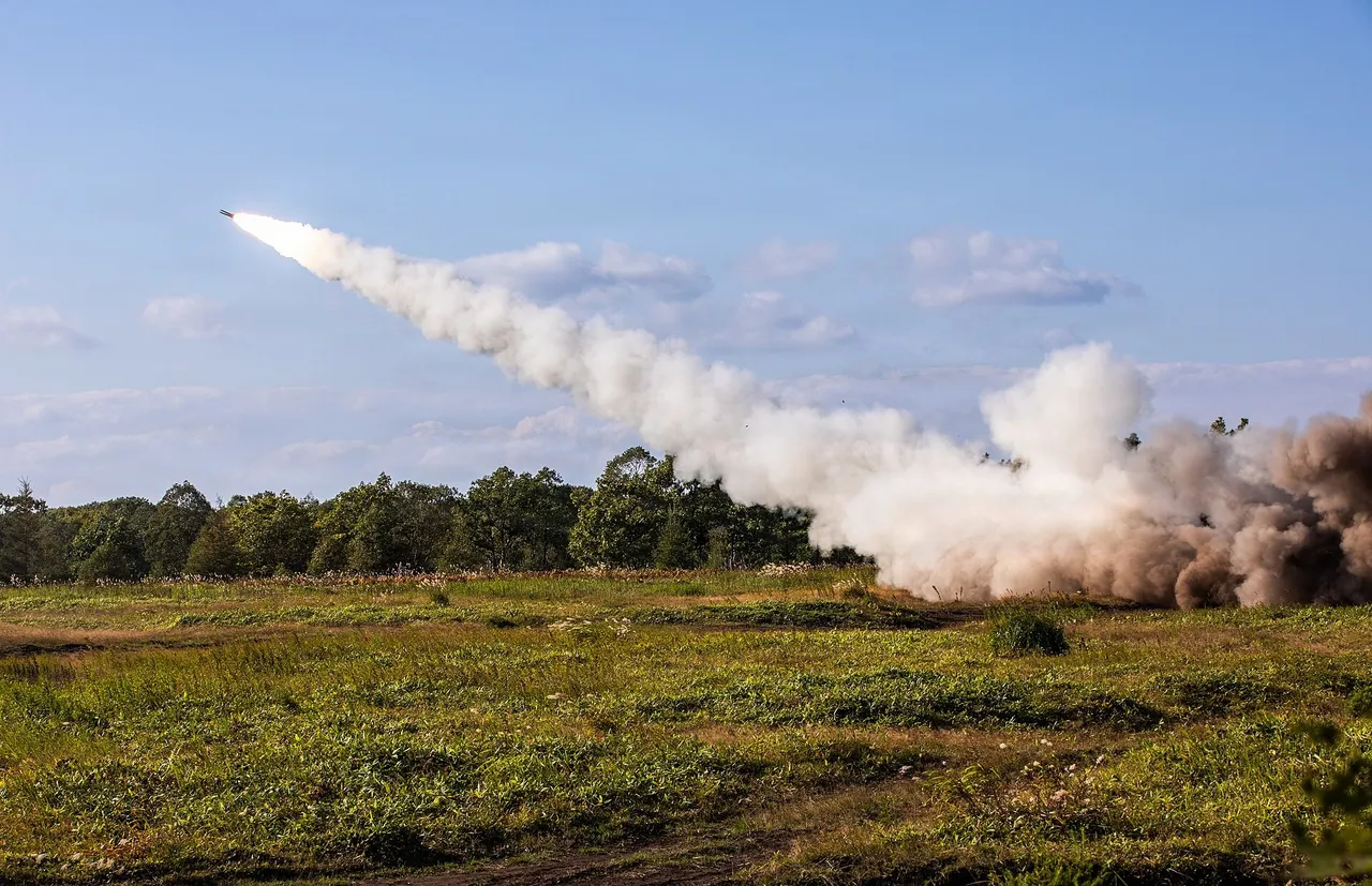 A US Army HIMARS rocket launcher truck fires a rocket in a burst of smoke and flame on a training range