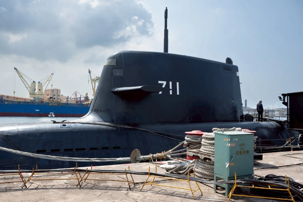 The black sail of Taiwan's Hai Kun submarine, marked 711, moored at a pier with cargo cranes in the background