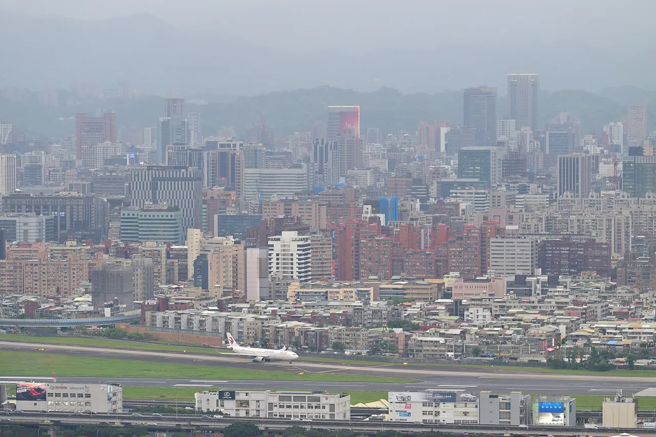 Airliner on the runway of Taipei Songshan Airport with dense city buildings and hills behind
