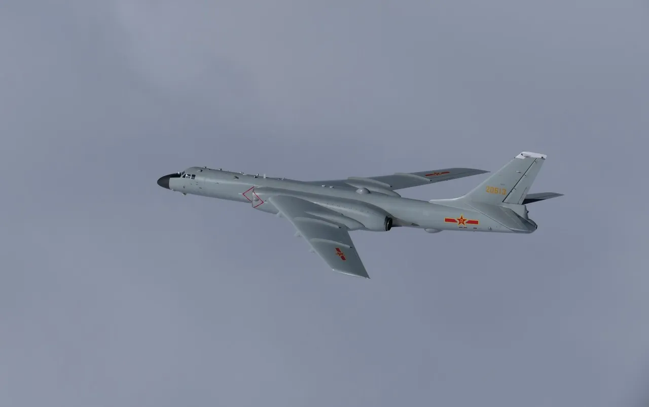 A grey Chinese H-6K bomber with red star markings flying against an overcast sky