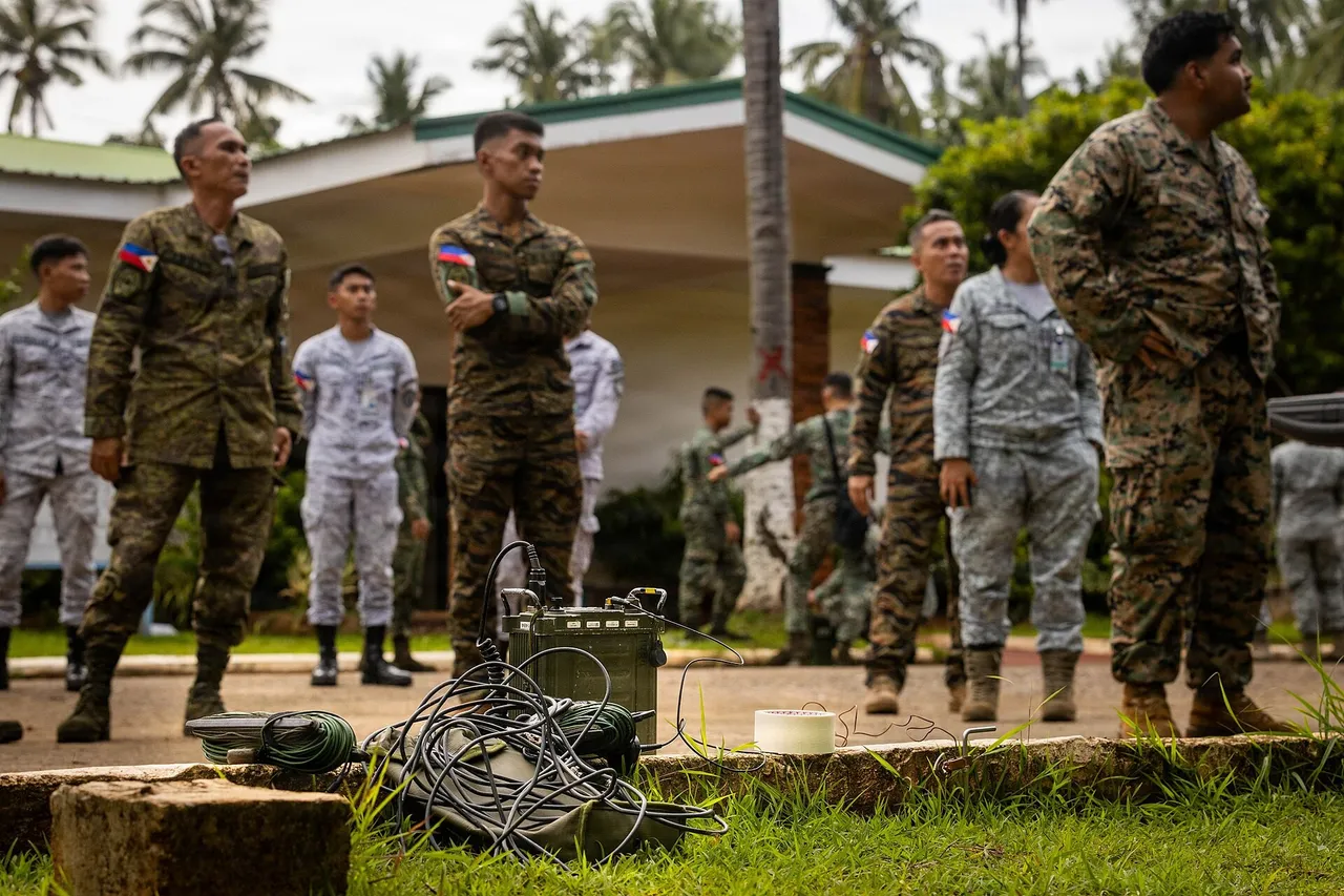 Philippine soldiers and airmen in camouflage uniforms stand outdoors near a building while a portable radio unit with coiled cables sits on the ground in front of them
