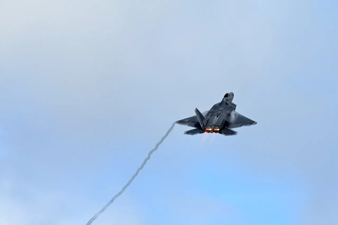 A grey F-22 Raptor stealth fighter climbing steeply away from a runway on a Pacific island