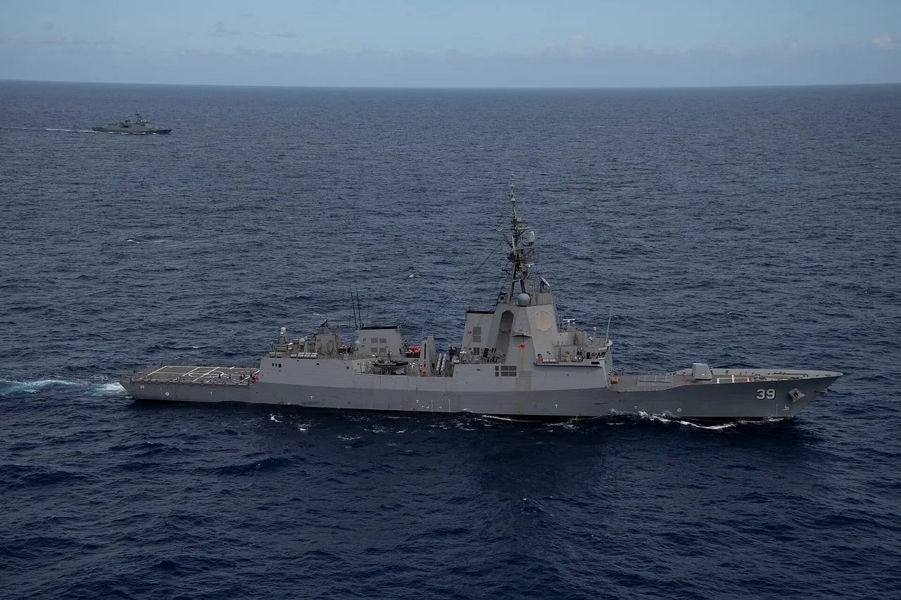 A grey Australian destroyer with the hull number 39 sails across a dark blue ocean, with another warship in the distance