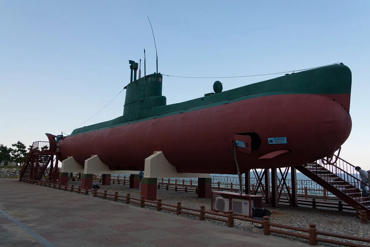 A green and red North Korean Sang-O class submarine displayed on land beside the sea at Gangneung, South Korea