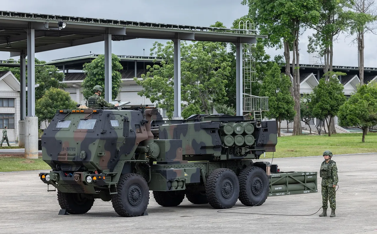 A camouflaged HIMARS rocket launcher truck with soldiers beside it on a base apron