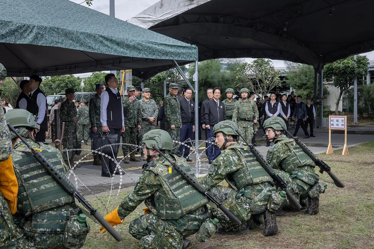 Helmeted reservists in camouflage kneel with rifles behind barbed wire on grass while officials and officers watch from under a tent