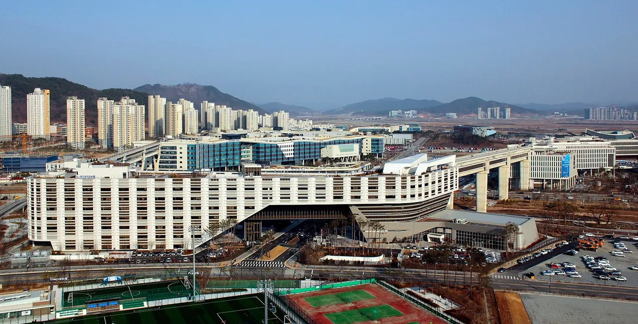 Aerial view of the long white government complex buildings in Sejong with apartment towers and hills behind