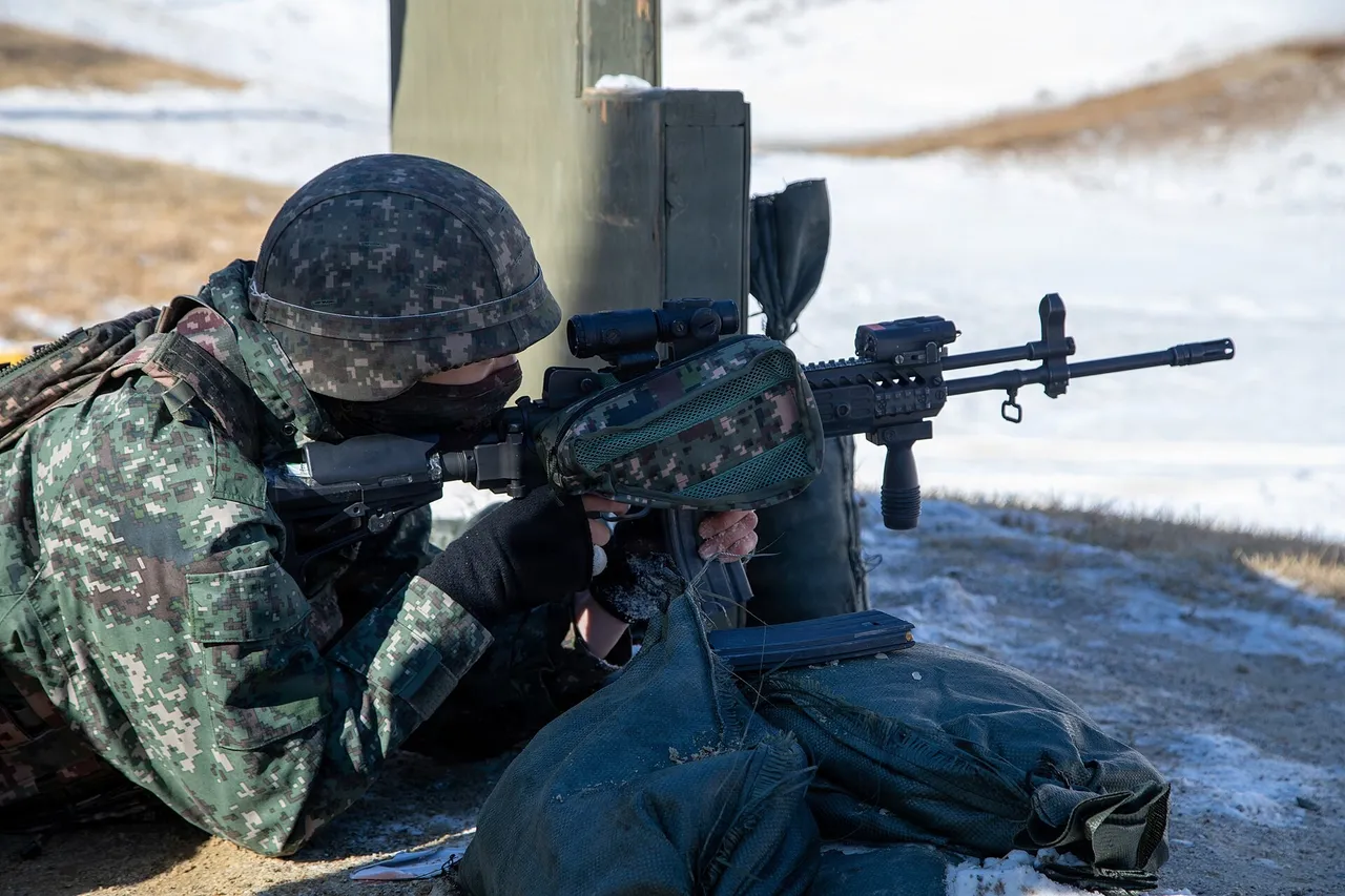 A South Korean soldier in camouflage and helmet lies prone and aims a scoped K2 rifle on a snowy firing range