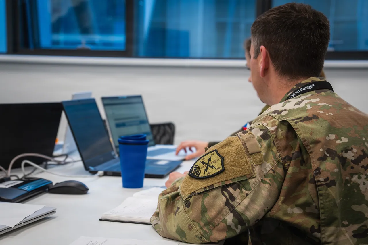 Soldiers seated at laptops and monitors in a cyber exercise room