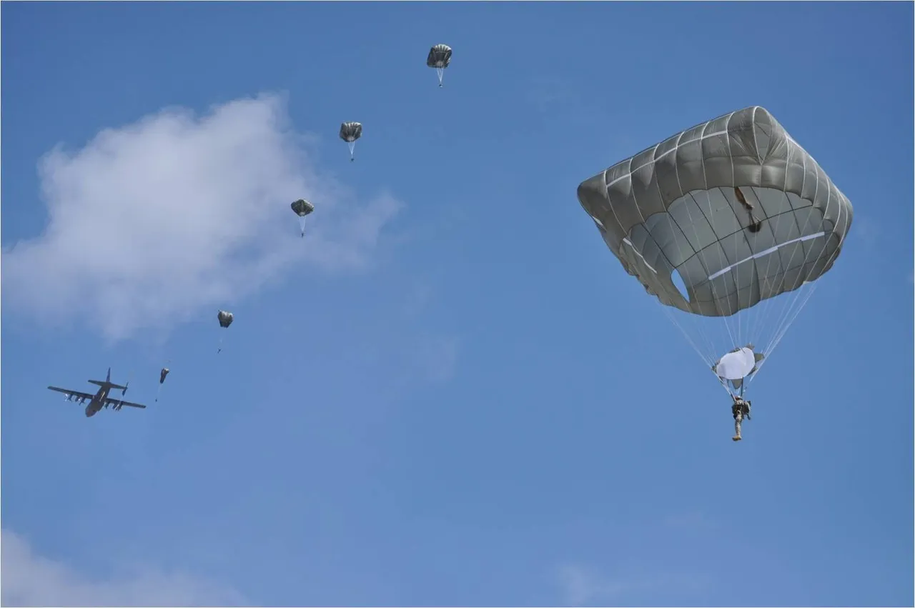 Paratroopers descend under grey-green T-11 canopies against a blue sky as a C-130 transport aircraft flies away on the left