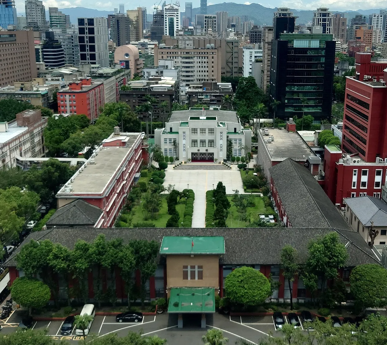Aerial view of the white Legislative Yuan main building in Taipei with a tree-lined courtyard, surrounded by city office blocks