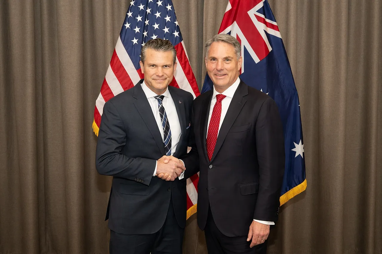 Pete Hegseth and Richard Marles shaking hands in front of US and Australian flags