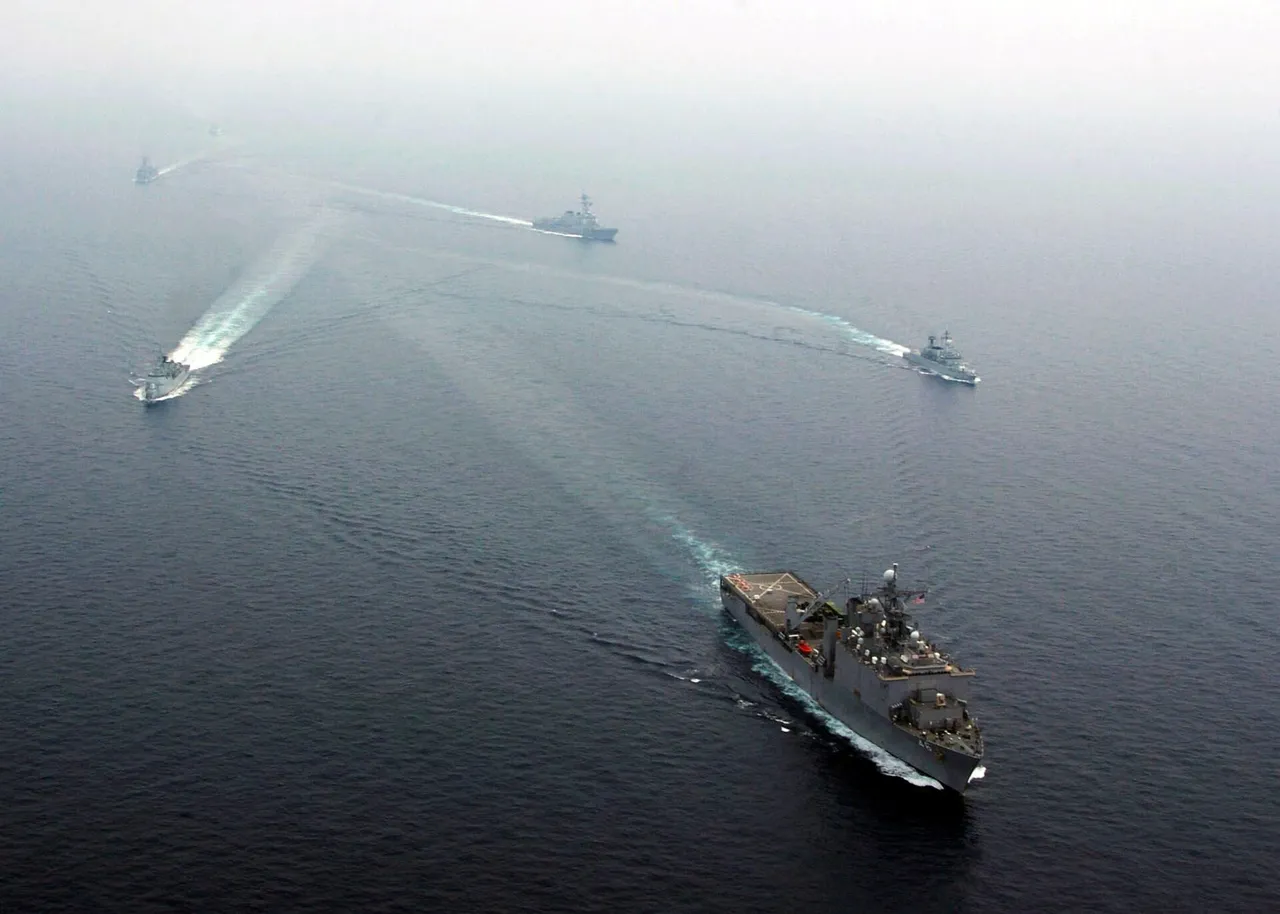 A line of grey warships sailing in formation across open sea under a hazy sky