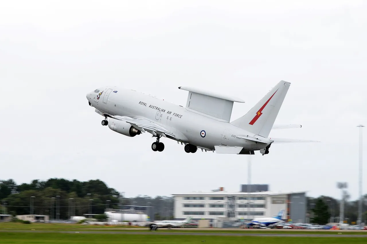 A grey airborne early warning aircraft with a large radar fin on its back climbs away from a runway