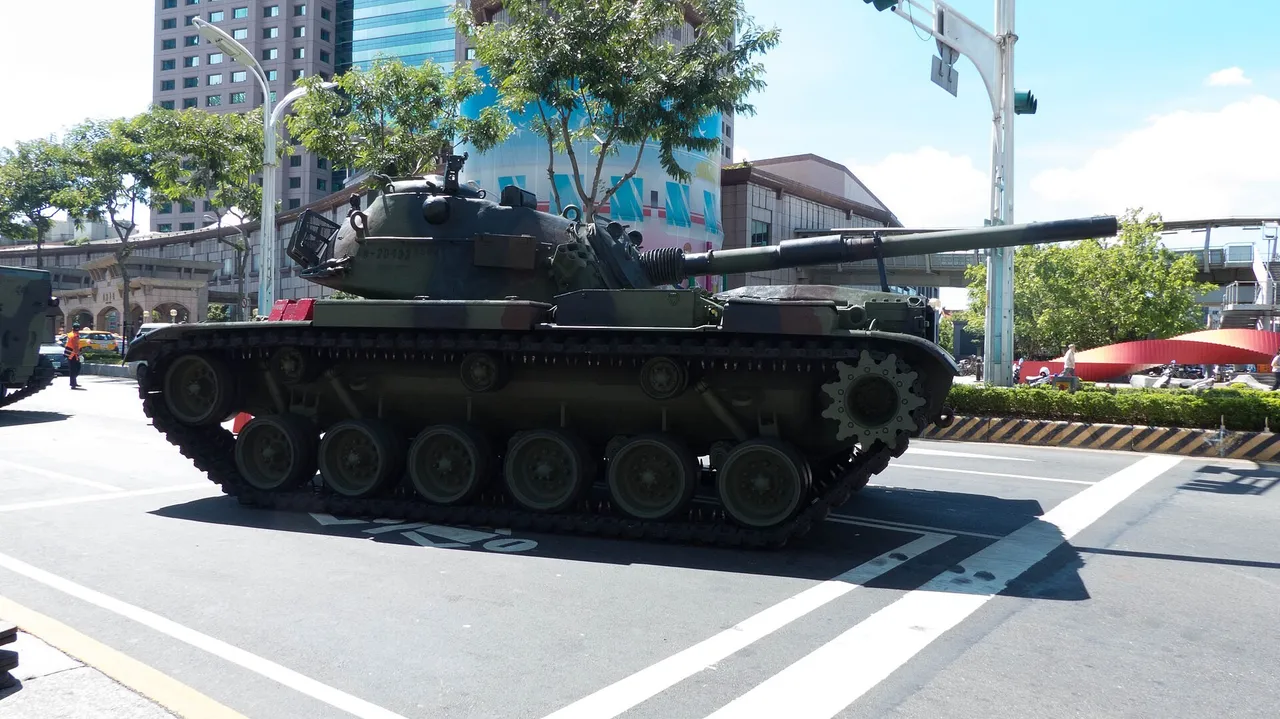 A camouflaged Taiwanese CM11 tank on its tracks on a paved city road beside office buildings