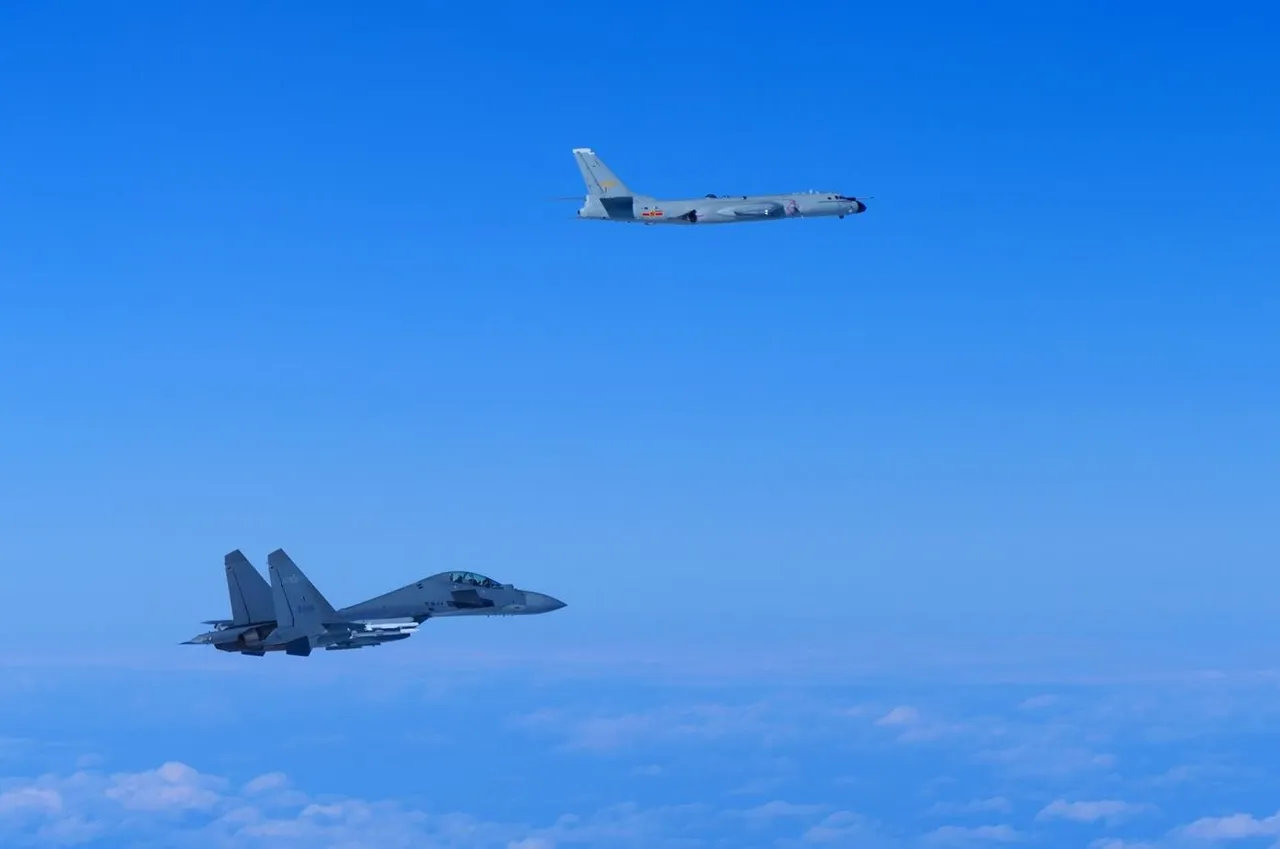 A grey Chinese H-6 bomber flying above a smaller grey J-16 fighter jet over the sea