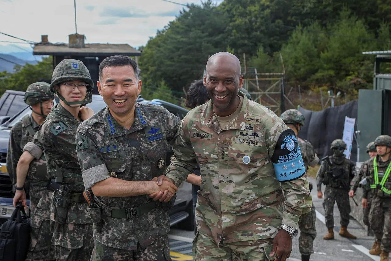 Two generals in camouflage uniforms shake hands at a military guard post as soldiers stand behind them