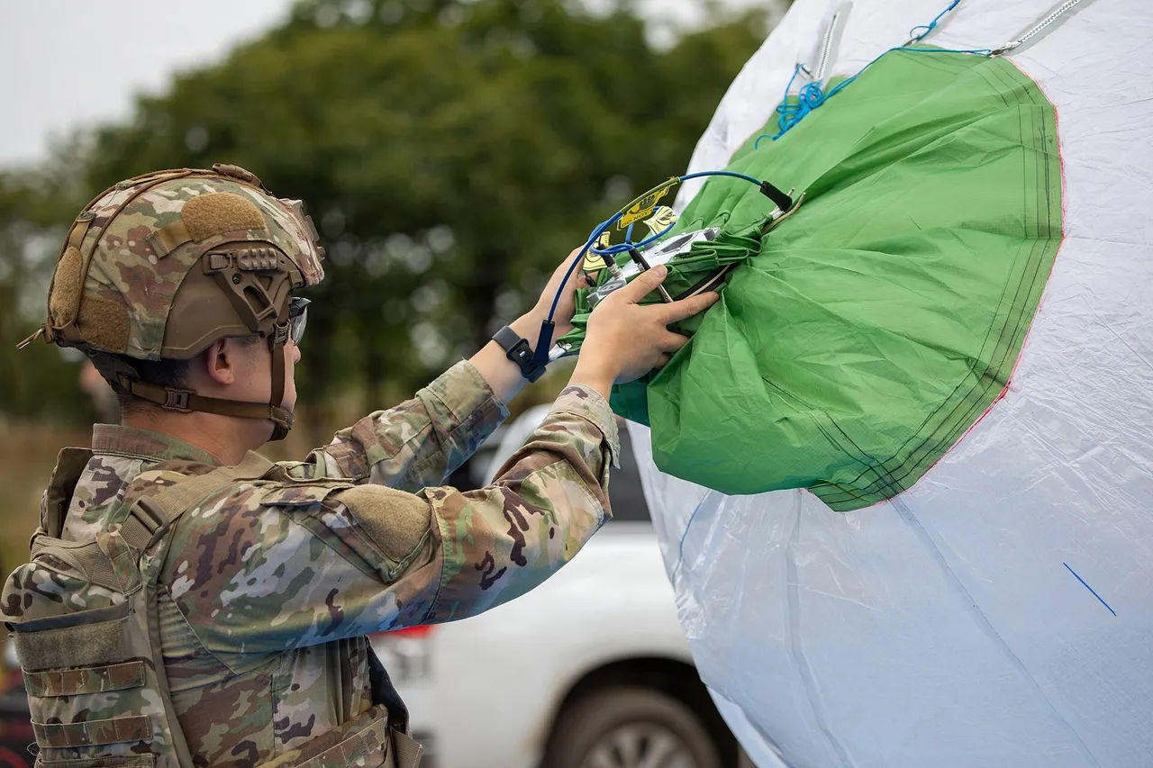 A US Army soldier in a helmet attaches equipment to a large white and green balloon envelope