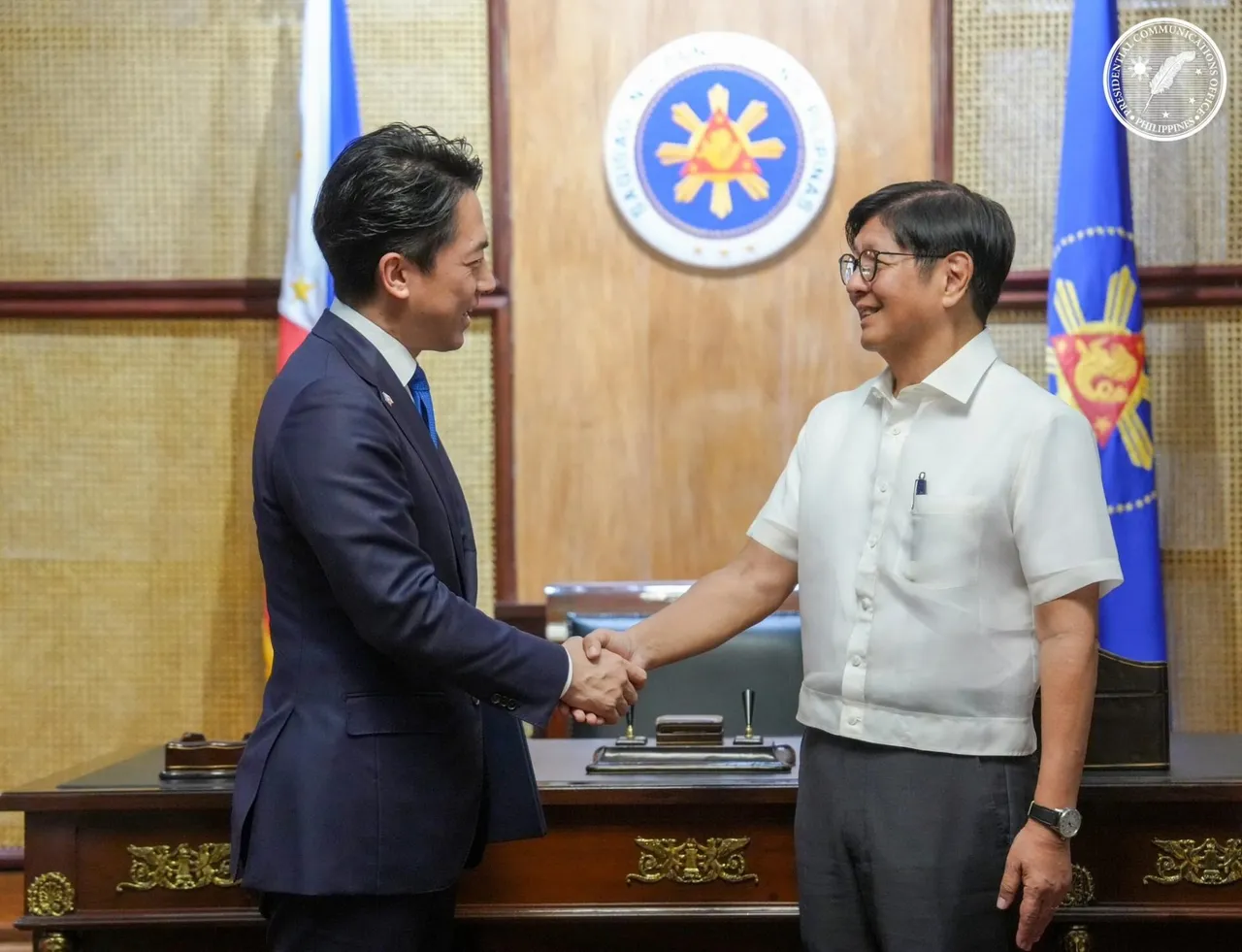 Japanese Defence Minister Shinjiro Koizumi shaking hands with Philippine President Ferdinand Marcos Jr. in an office with flags