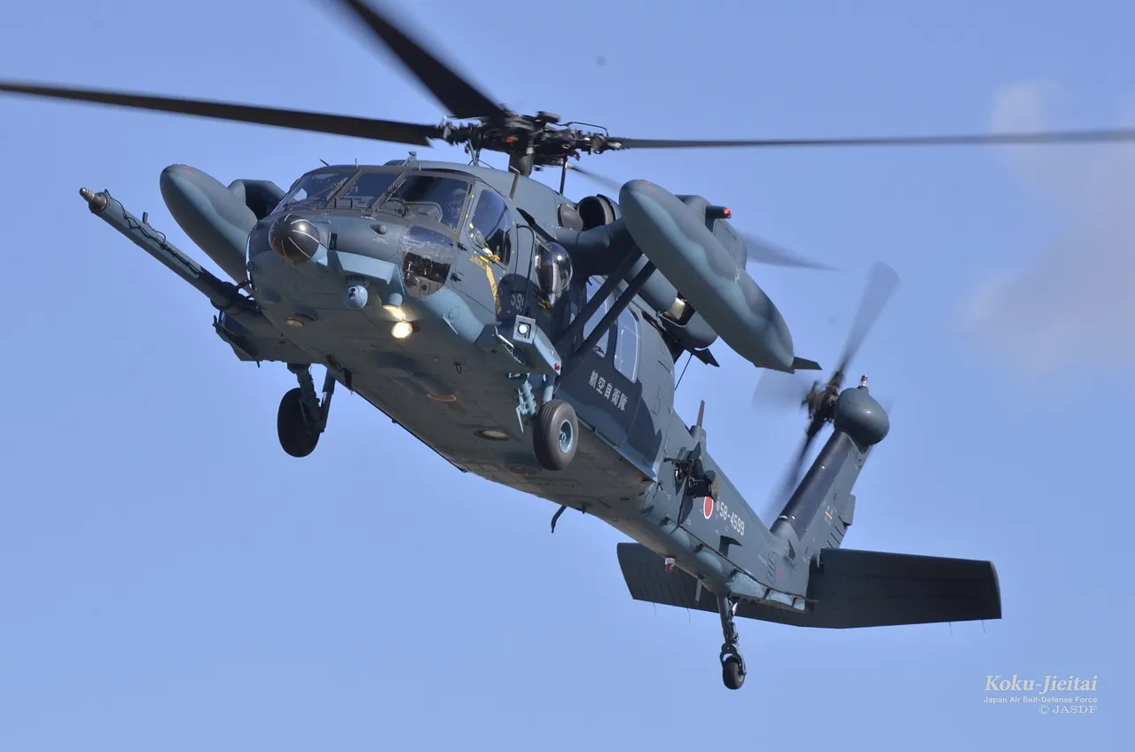 A grey Japan Air Self-Defense Force UH-60J rescue helicopter flying against a blue sky