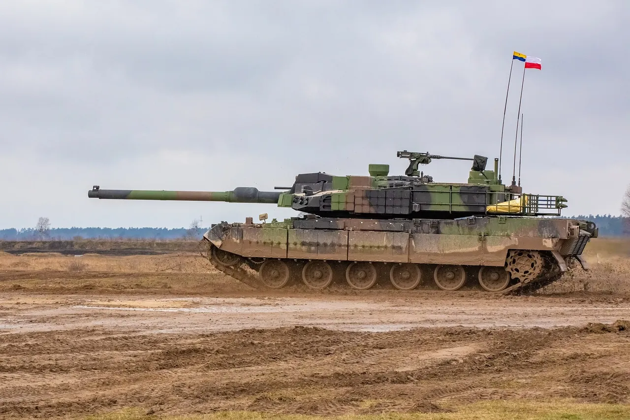 A camouflaged K2 main battle tank with a long gun barrel drives across a muddy training range under a grey sky