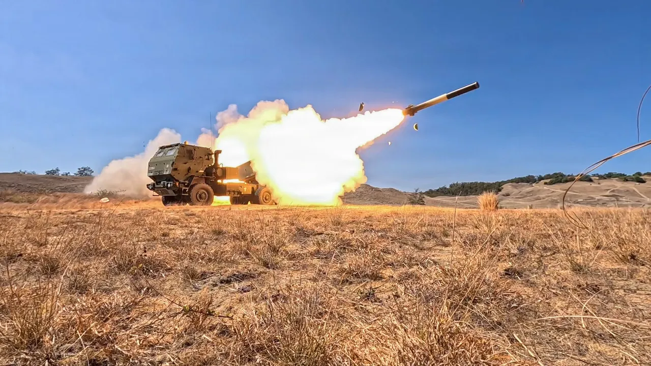 A US Army HIMARS truck launches a rocket in a burst of flame and smoke across dry grassland under a clear blue sky