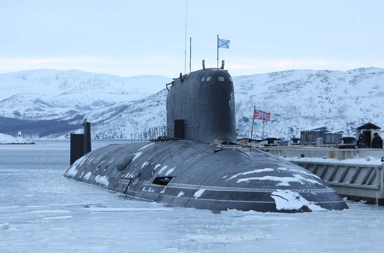 A large black Russian nuclear submarine moored at an icy pier with snow-covered hills behind it