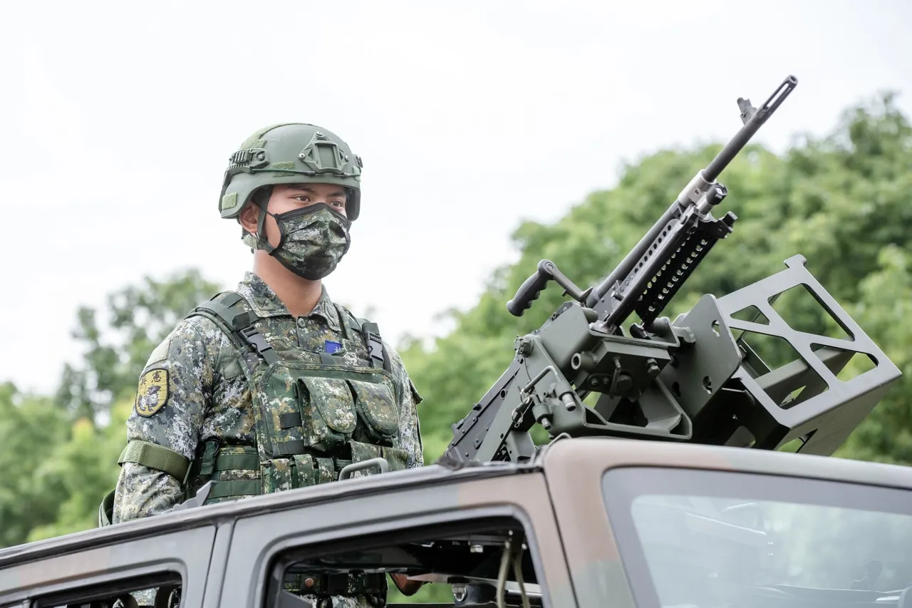 A Taiwanese soldier in camouflage, helmet and face mask stands in the roof hatch of a vehicle beside a mounted machine gun, with trees behind