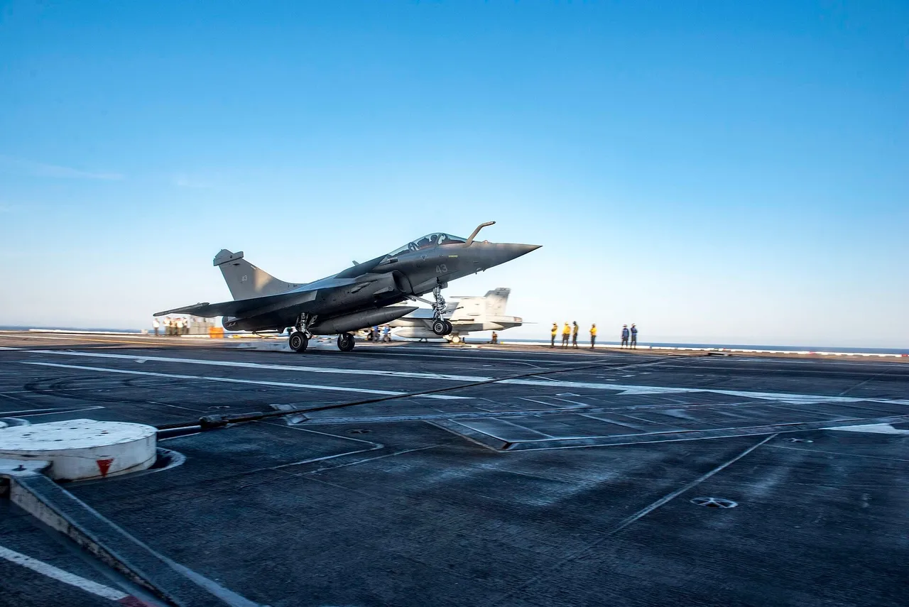 Grey Rafale M naval fighter with tailhook down touching down on the flight deck of an aircraft carrier at sea