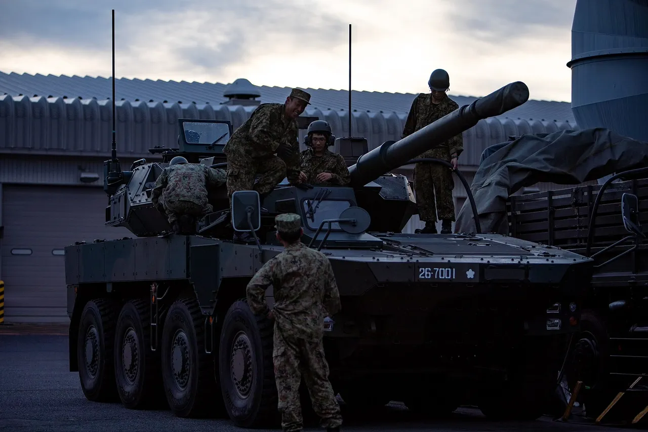 Japanese soldiers stand beside a wheeled Type 16 maneuver combat vehicle on an air base apron