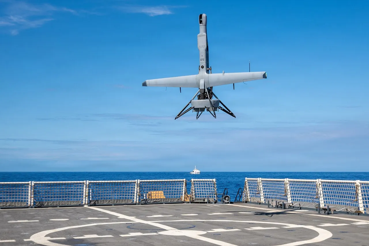 A small grey ducted-fan V-BAT drone descends tail-first onto the flight deck of a white US Coast Guard cutter at sea
