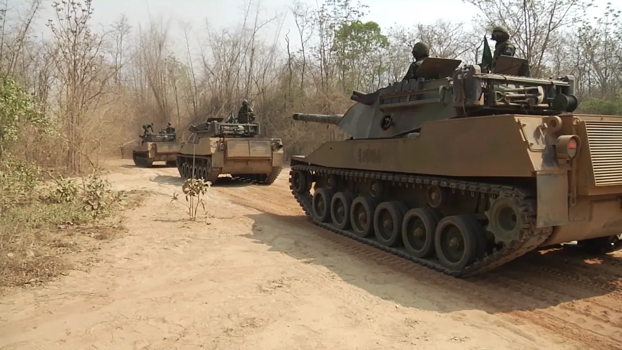 Three tan Royal Thai Army Stingray light tanks with crew in the turrets driving along a dirt track through dry forest