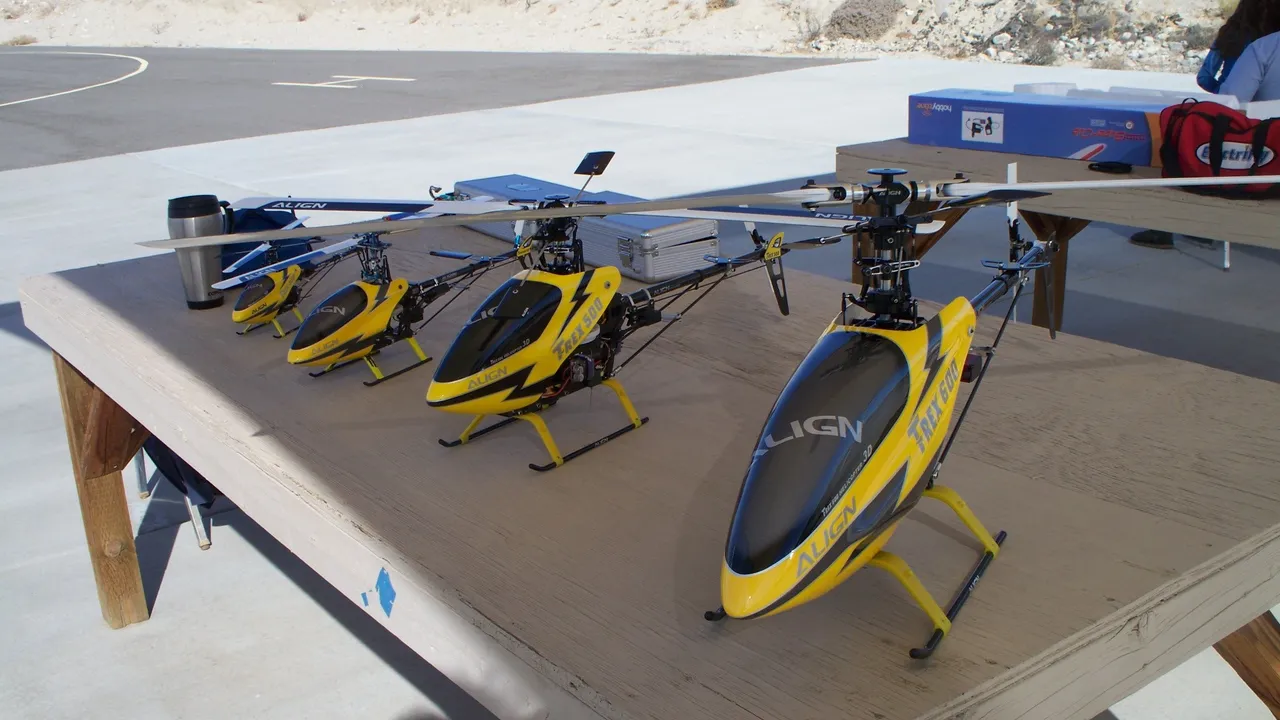 Four Align T-REX radio-controlled model helicopters of increasing size lined up on the ground