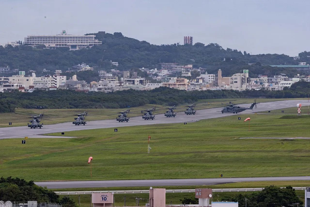 Rows of US Marine Corps helicopters and tiltrotor aircraft parked closely on an airfield runway under a clear sky