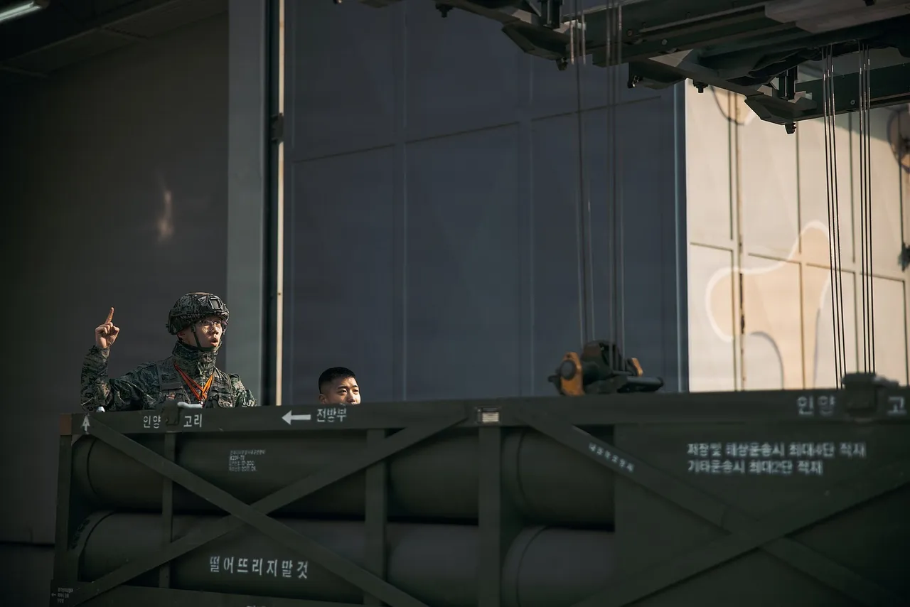 A South Korean Marine in camouflage gestures beside a K239 Chunmoo rocket pod inside a hangar on Yeonpyeong Island