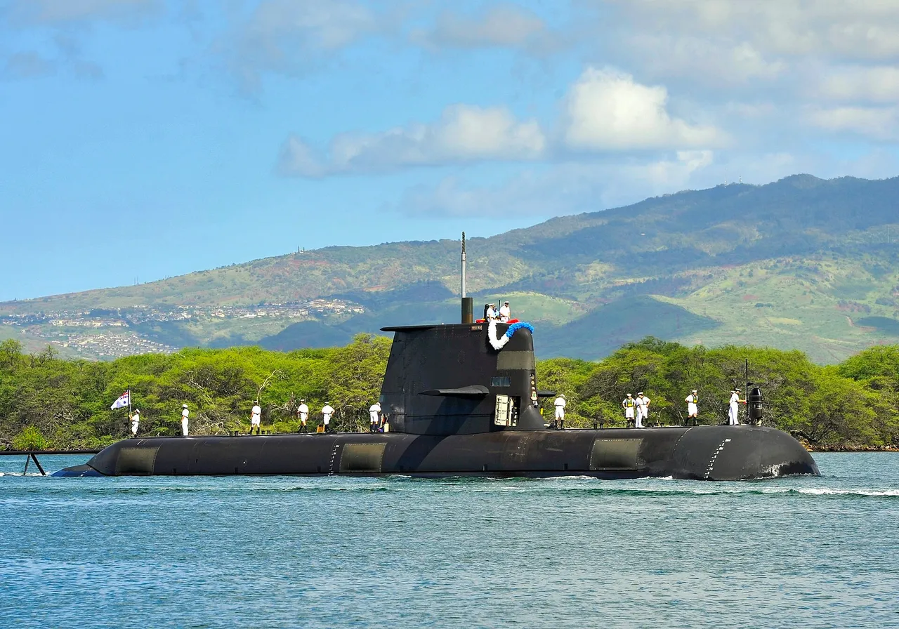 A dark grey submarine with its fin and crew on deck sails into harbour on calm blue water