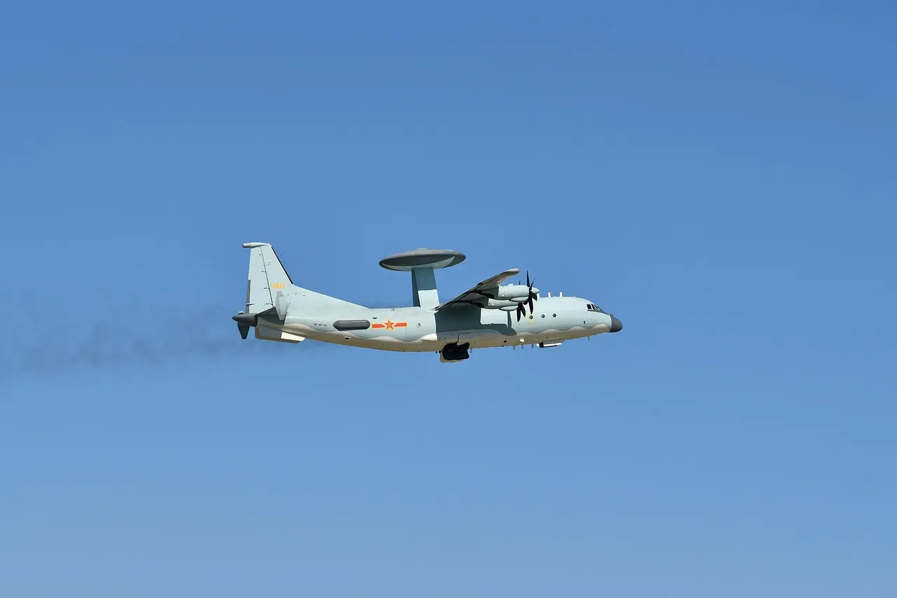 A grey four-propeller Chinese military aircraft with a large disc-shaped radar dome on its back flies against a blue sky