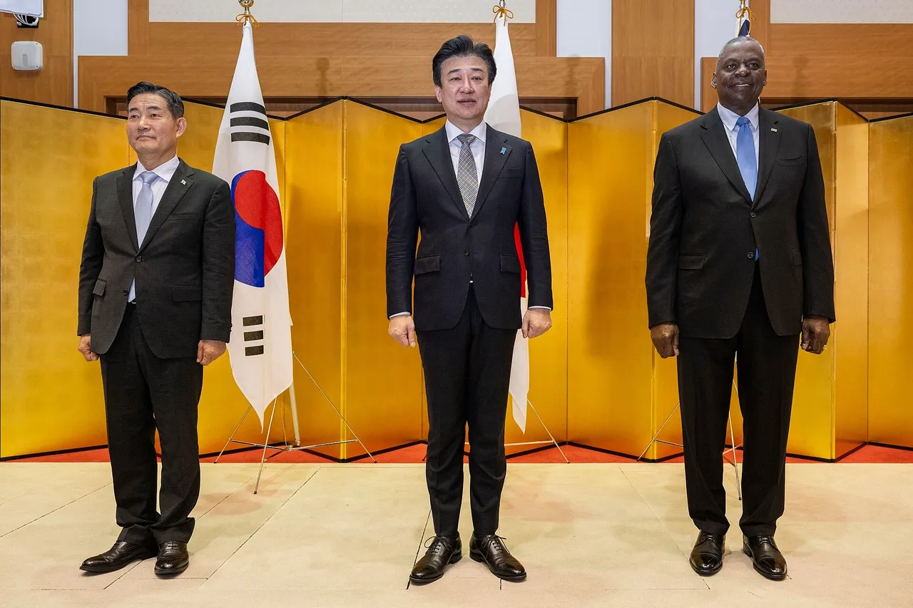 Three defence ministers and their delegations seated around a conference table at a trilateral meeting in Tokyo