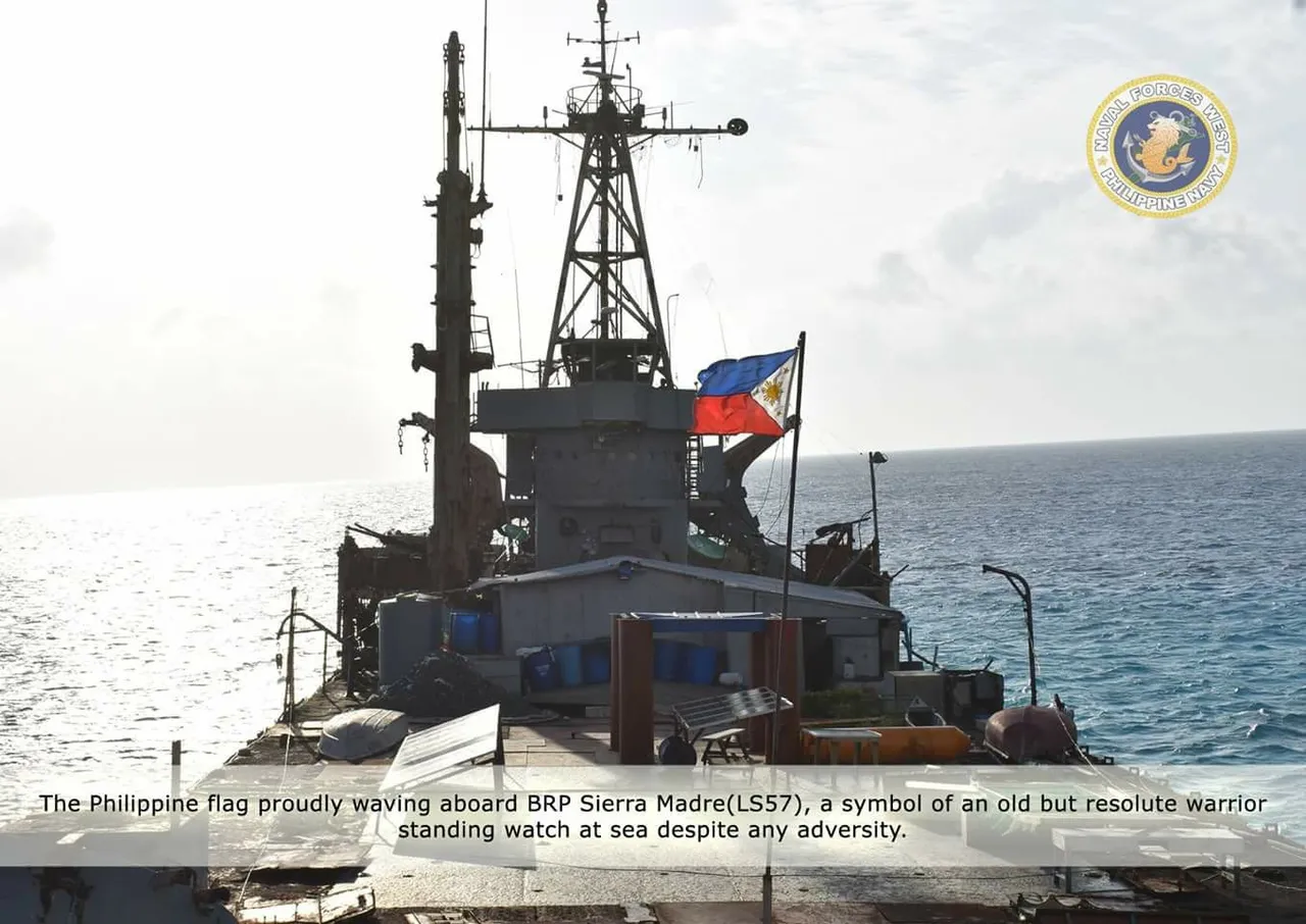 The Philippine flag flies above the rusting deck and mast of the grounded BRP Sierra Madre, with open sea behind it.