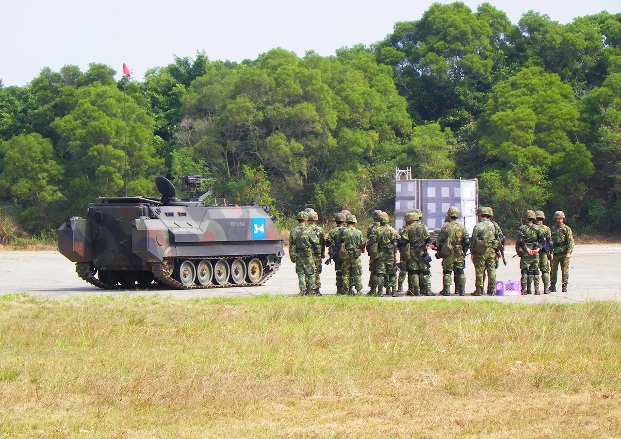 A group of Taiwanese army soldiers in camouflage and helmets standing in formation next to a tracked armoured personnel carrier on an airfield