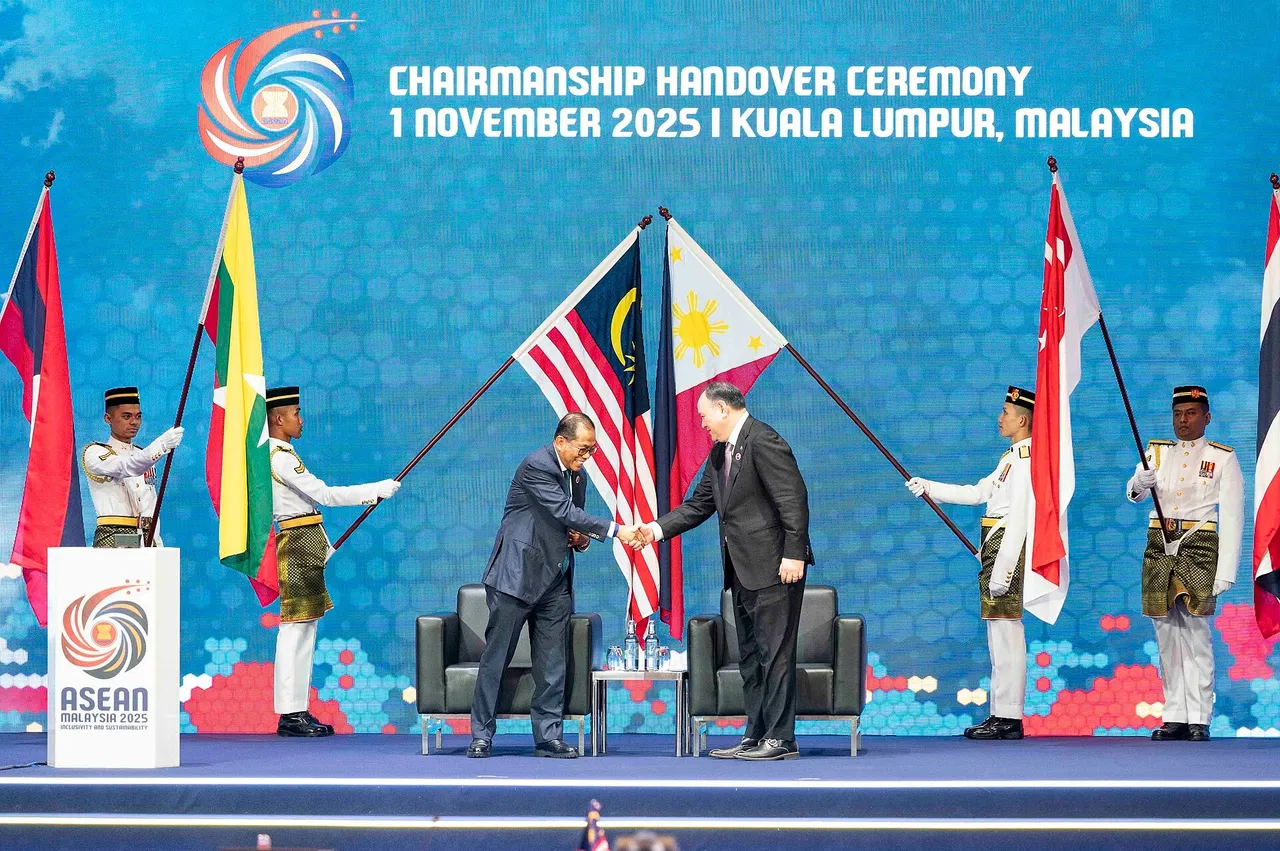 Malaysian defence minister handing over the ASEAN defence ministers' meeting chairmanship to Philippine Defense Secretary Gilberto Teodoro on a stage