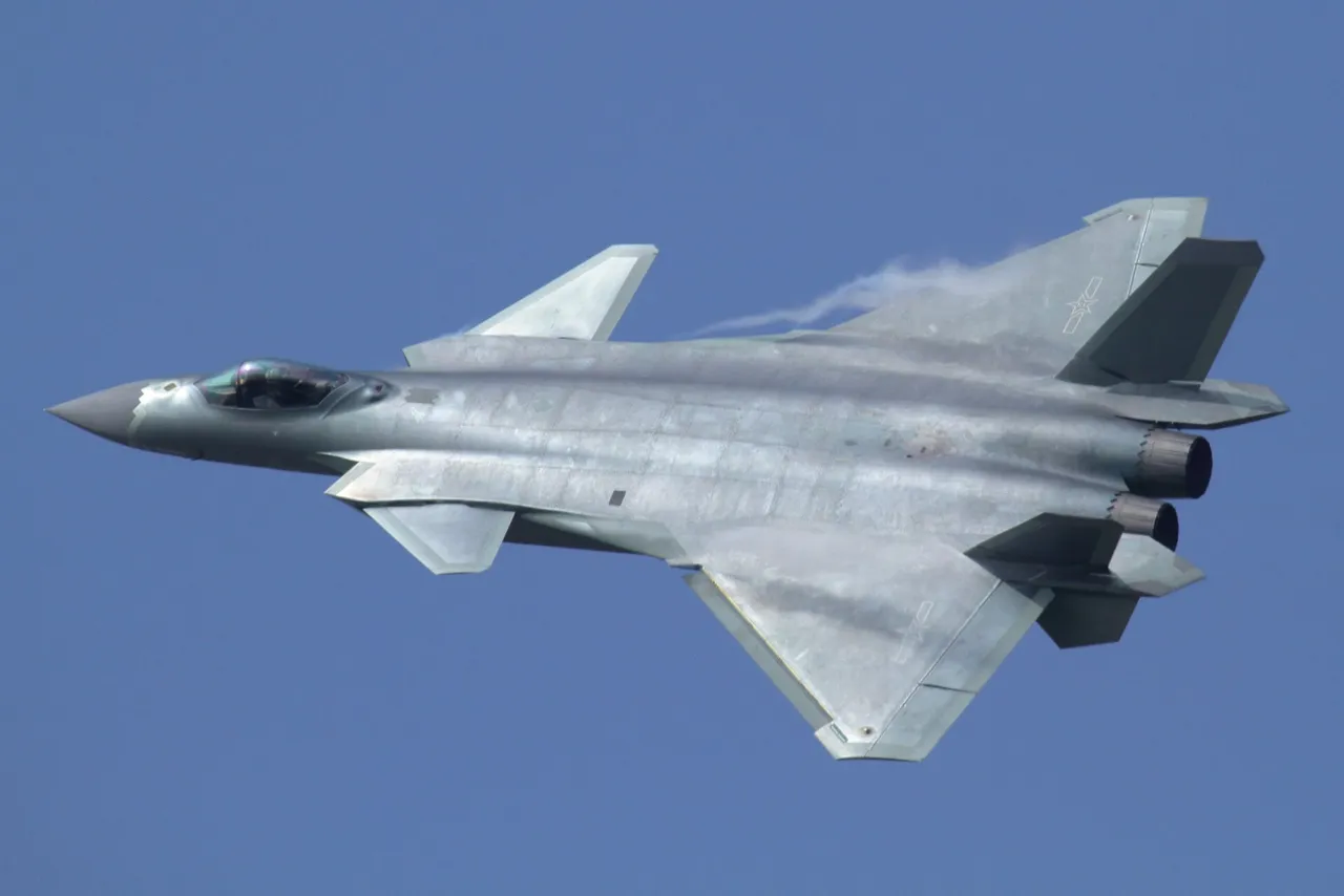 A grey twin-engine stealth fighter jet with canard foreplanes flies against a pale sky