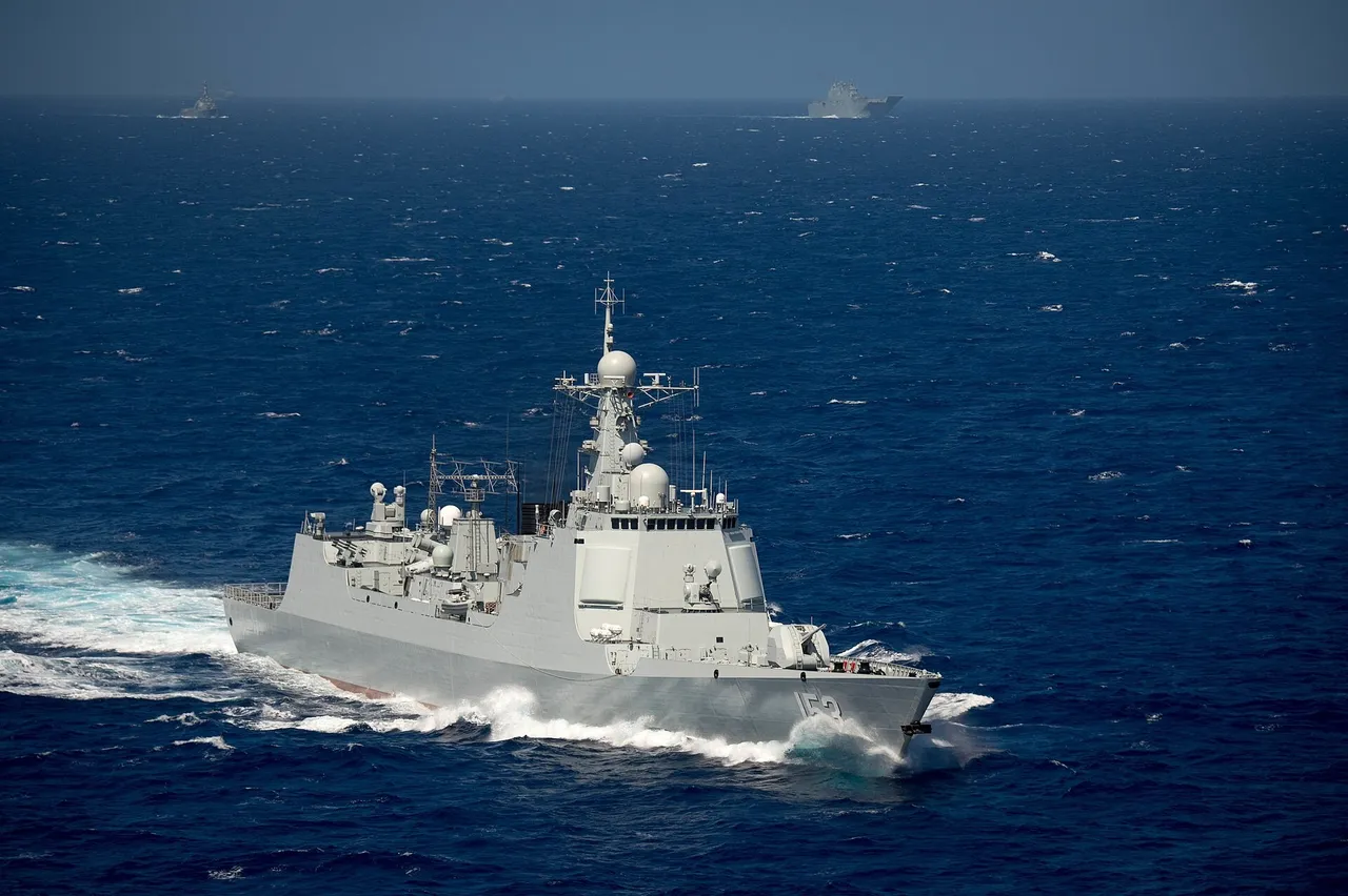 A grey Chinese navy destroyer with hull number 153 cutting through deep blue water, with two other warships on the horizon
