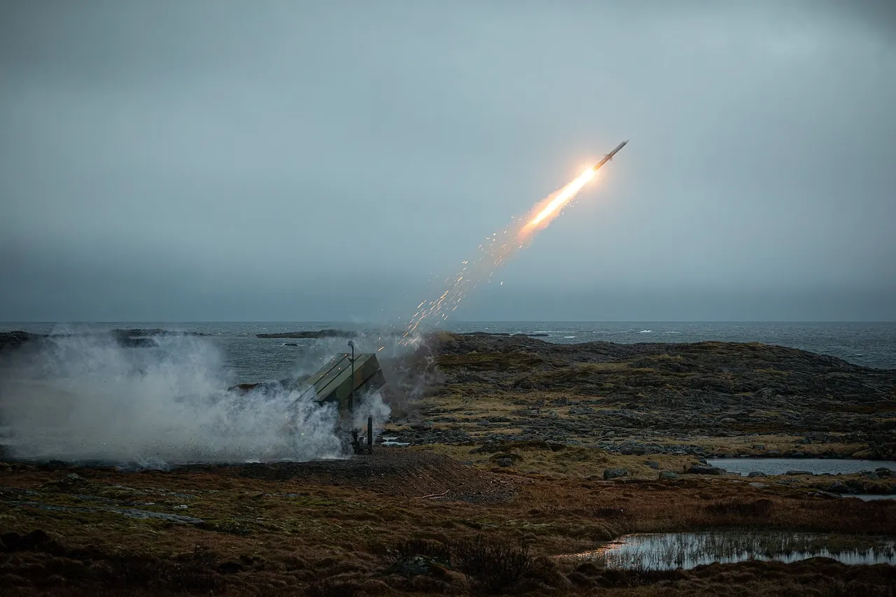 A missile climbs on a bright flame trail from a box launcher on a rocky coastal heath under a grey sky