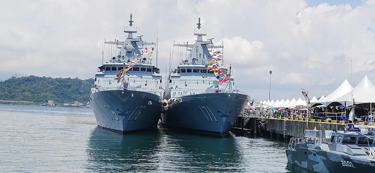 Two grey Royal Malaysian Navy patrol ships moored side by side at a naval base pier