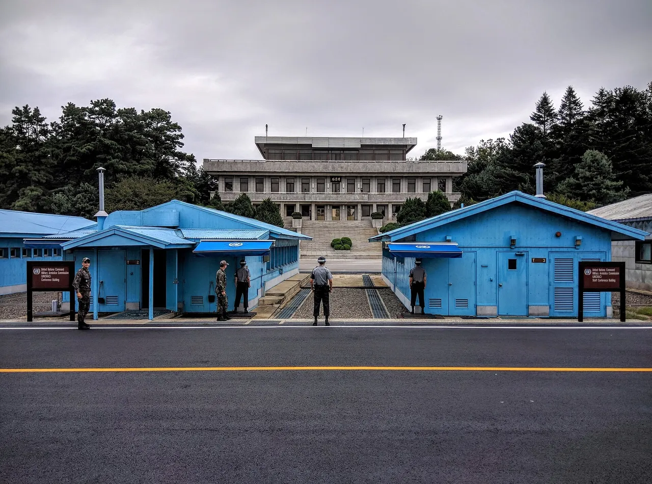 South Korean soldiers stand between blue conference buildings at the Joint Security Area in Panmunjom, with a large North Korean building behind them