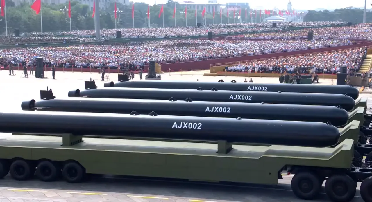 Long black cylindrical underwater drones marked AJX002 on military transporters in front of packed grandstands and red flags